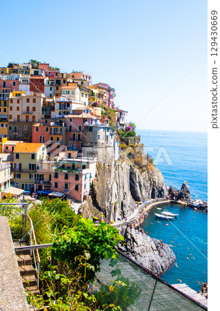 Multicolored houses on cliff edge. Manarola Italian village Cinque Terre, Liguria, Italy city architecture Multicolored houses on cliff edge. Manarola Italian village Cinque Terre, Liguria, Italy city architecture 129430669