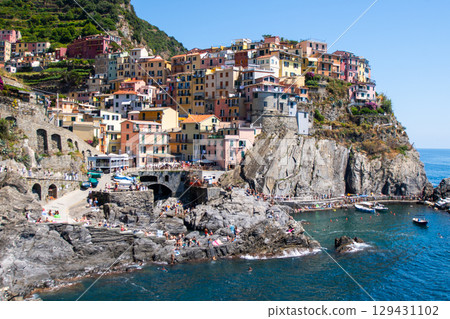 Multicolored house on cliff edge. Manarola Italian village Cinque Terre, Liguria, Italy. Summer sea Multicolored house on cliff edge. Manarola Italian village Cinque Terre, Liguria, Italy. Summer sea 129431102