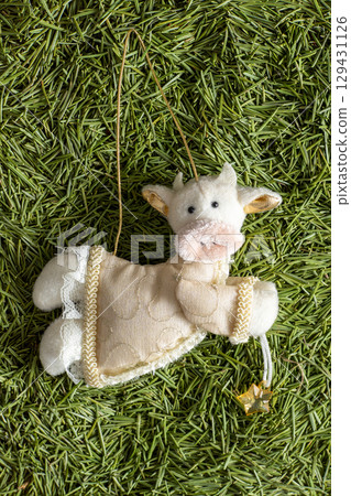Cow soft toy decoration. Christmas tree toy with green needles in the background Cow soft toy decoration. Christmas tree toy with green needles in the background 129431126