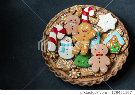 Gingerbread cookies with icing decoration. Christmas food. Gingerbread man baking. Xmas sweet on black background copy space 129431197