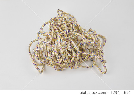 A tangled heap of rope lies on a plain white surface A tangled heap of rope lies on a plain white surface 129431695