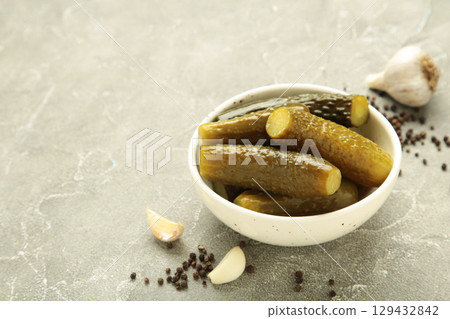 Marinated pickled cucumber with garlic on grey concrete background. Marinated pickled cucumber with garlic on grey concrete background. 129432842
