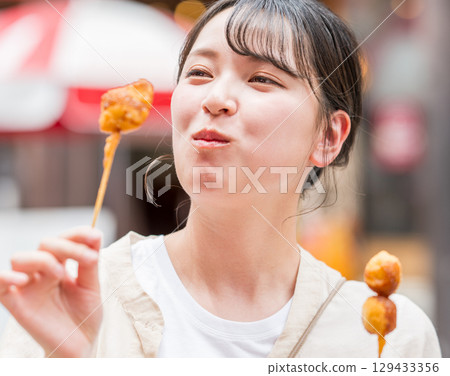 大阪府大阪市道頓堀,一名女子在戶外享用炸串 大阪府大阪市道頓堀,一名女子在戶外享用炸串 129433356