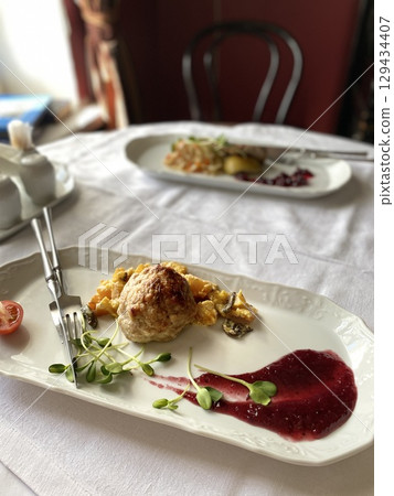 Gourmet chicken dish served with colorful garnishes on elegant white plate in restaurant setting 129434407