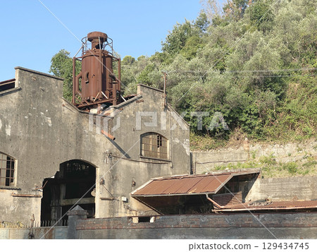 Buildings of old factory. Ruins and rusty structures. Old dilapidated building and nature. 129434745