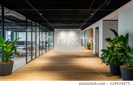 A modern office interior featuring a large blank white wall, clean flooring and floor-to-ceiling windows.  129434873