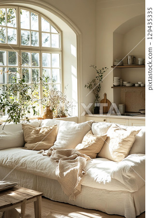 Bright white kitchen interior with comfortable sofa basking in sunlight on a clear day 129435335