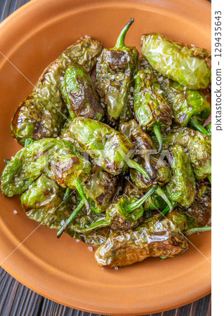 Terracotta bowl of Pimientos de Padron sprinkled with coarse sea salt 129435643