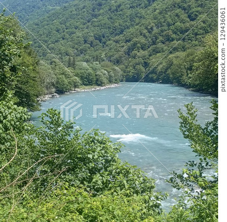 A serene river valley landscape in a natural style, in vibrant green and blue colors, representing pristine nature and tranquility, with copy space A serene river valley landscape in a natural style, in vibrant green and blue colors, representing pristine nature and tranquility, with copy space 129436061