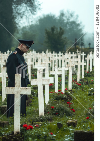 Soldier pays tribute at military cemetery during a misty morning 129436082