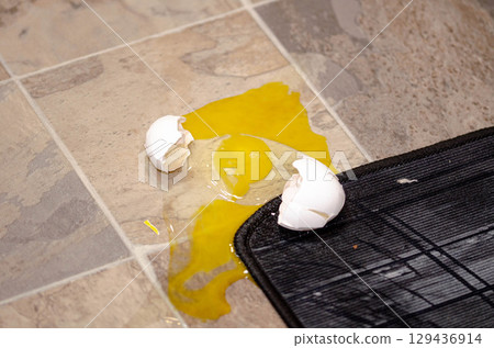 Cracked Broken Egg Spilled on Kitchen Floor 129436914