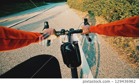 Point of view shot of a cyclist riding a road bike uphill on a sunny early morning while shadows stretch along the road Point of view shot of a cyclist riding a road bike uphill on a sunny early morning while shadows stretch along the road 129436962
