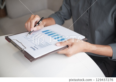 Closeup hand of  businessman reading report in office 129437276
