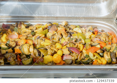 Colorful mix of grilled zucchini, bell peppers, onions, and eggplant in a stainless steel chafing dish. Perfect for catering, healthy eating concepts, restaurant menus, and event buffet visuals. 129437339