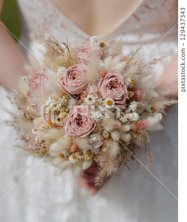Close-up of a bridal bouquet with soft pink roses, dried flowers, and delicate textures. Perfect for wedding invitations, floral design, romantic events, and bridal marketing Close-up of a bridal bouquet with soft pink roses, dried flowers, and delicate textures. Perfect for wedding invitations, floral design, romantic events, and bridal marketing 129437343