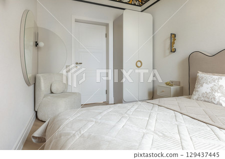 Cozy Bedroom with Round Mirror and Soft Armchair 129437445
