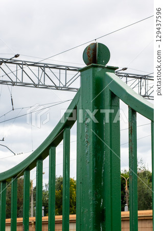 A green fence with a metallic structure stands in the background A green fence with a metallic structure stands in the background 129437596
