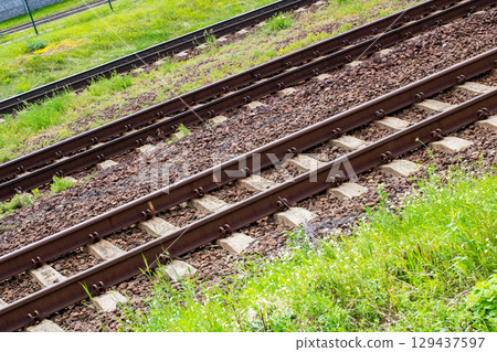 Closeup of a worn train track with grass growing on it 129437597