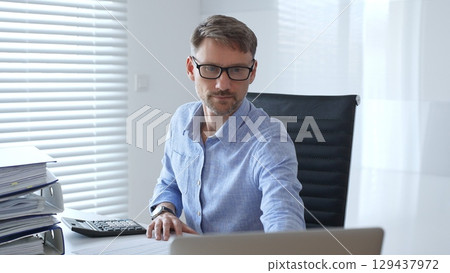 Male professional accountant calculating invoices and managing bills while reviewing financial reports in an office setting. Audit and taxes theme in business 129437972
