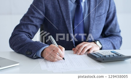Professional accountant is examining financial documents, magnifying glass in hand, calculator positioned on sleek desk workspace. Audit and taxes in business 129438005