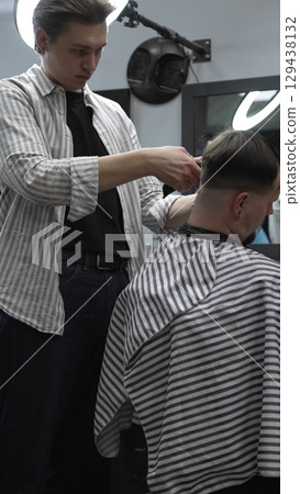 Professional barber carefully trimming customer's hair with electric clipper, providing a stylish and precise haircut in a modern barbershop environment Professional barber carefully trimming customer's hair with electric clipper, providing a stylish and precise haircut in a modern barbershop environment 129438132