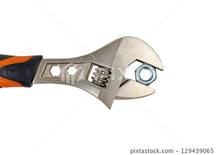 Adjustable wrench held with a metal nut on a white background. High quality photo 129439065