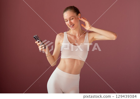 Healthy lifestyle enthusiast in sportswear with headphones and smartphone, tracking workout performance and staying committed to active living and fitness goals. Healthy lifestyle enthusiast in sportswear with headphones and smartphone, tracking workout performance and staying committed to active living and fitness goals. 129439384