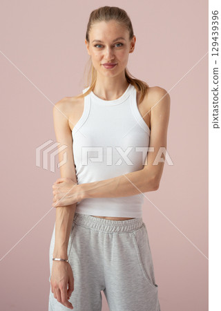 Female in athletic lounge outfit posing against plain pink background Female in athletic lounge outfit posing against plain pink background 129439396