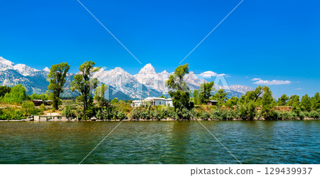 Menors Ferry Historic District in Grand Teton National Park, Wyoming, USA, with rustic cabins, cottonwood trees, and the Teton Range on a bright summer day Menors Ferry Historic District in Grand Teton National Park, Wyoming, USA, with rustic cabins, cottonwood trees, and the Teton Range on a bright summer day 129439937
