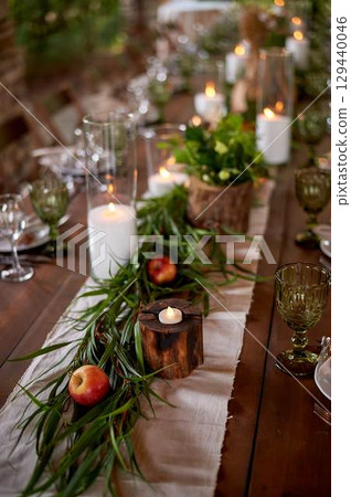 Banquet decoration in a simple rustic style with grass, greenery, simple objects and fabrics. Wedding table setting for guests 129440046