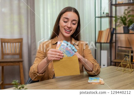 Woman counting euro cash money placing bills into envelope pleased with careful budget planning 129440212