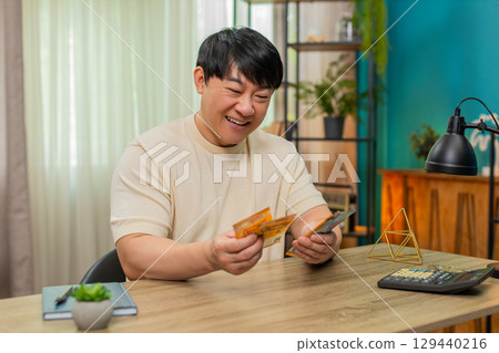 Asian man counting happily money euro cash pleased with earned income celebrates big financial gain Asian man counting happily money euro cash pleased with earned income celebrates big financial gain 129440216