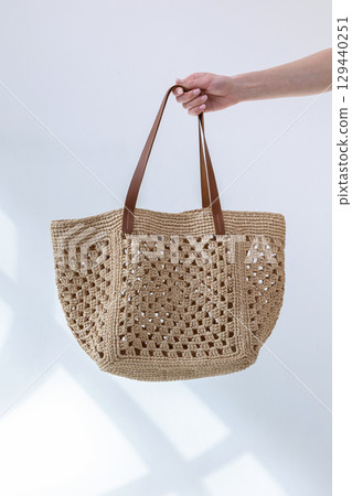 Female hand holding fashionable woven bag. Fashion and luxury accessories. Vertical photo. High quality photo Female hand holding fashionable woven bag. Fashion and luxury accessories. Vertical photo. High quality photo 129440251