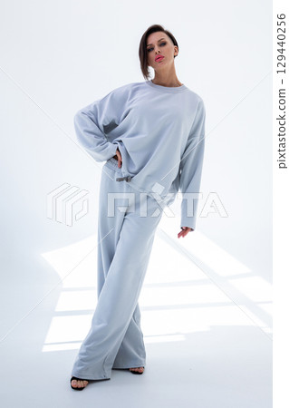 Young woman in gray sweatshirt and pants on white background. Studio photography. Vertical photo. High quality photo 129440256