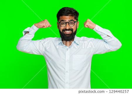 Indian man confidently smiling flexing arms showing muscles strength power pride motivation gesture 129440257