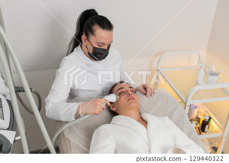 Woman gets RF lifting therapy under eyes with modern device in beauty cosmetology clinic session Woman gets RF lifting therapy under eyes with modern device in beauty cosmetology clinic session 129440322