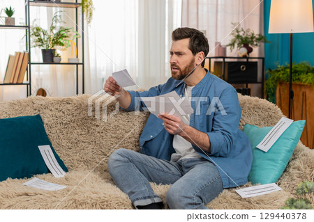Man throwing home utility bills on sofa, desperate about financial debt, frustration 129440378