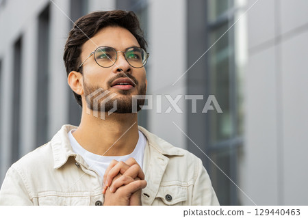 Portrait of Indian man praying with closed eyes to God asking for blessing help forgiveness outdoors 129440463