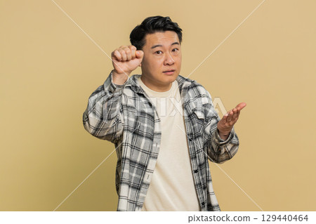 Confused excited Asian man knocking door gesture asking who is at home, feeling embarrassed, no idea 129440464