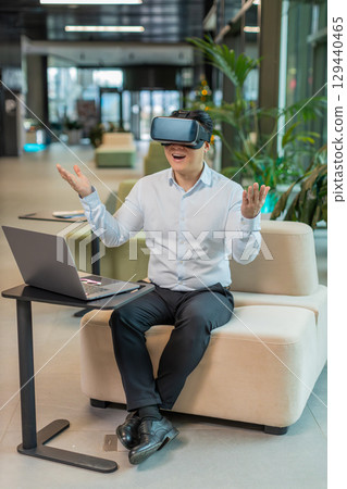 Mature businessman software developer using headset app making presentation in modern office lobby Mature businessman software developer using headset app making presentation in modern office lobby 129440465