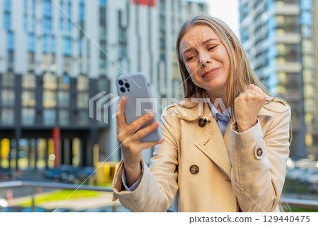 Upset businesswoman using smartphone browsing, loses becoming shocked bad news on downtown street Upset businesswoman using smartphone browsing, loses becoming shocked bad news on downtown street 129440475
