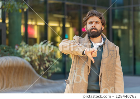 Upset young Indian man tourist showing thumb down expressing discontent on downtown city street 129440762