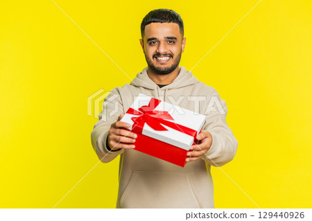 Smiling man presenting birthday gift present box stretches out hands, promotion discount sale Smiling man presenting birthday gift present box stretches out hands, promotion discount sale 129440926