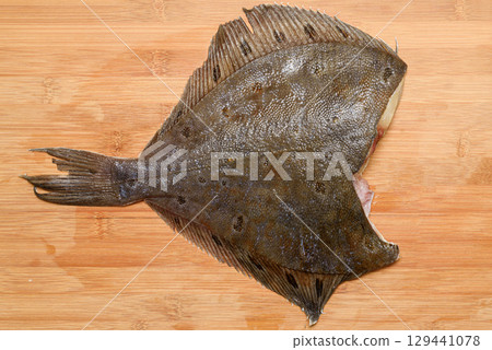 Thawed headless flounder on a cutting board. 129441078