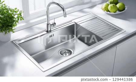 Modern stainless steel kitchen sink with faucet showcasing clean design and organization in bright interior setting 129441386