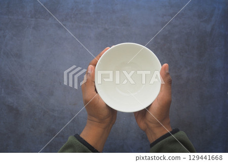 Hands with a white bowl on a textured surface 129441668