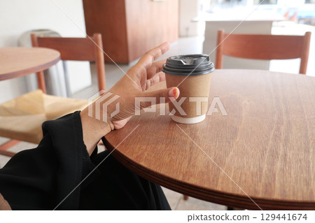 Hand holding a cup of coffee in a cozy cafe setting 129441674