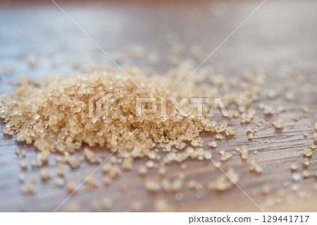 Sugar granules scattered on wooden surface close up 129441717
