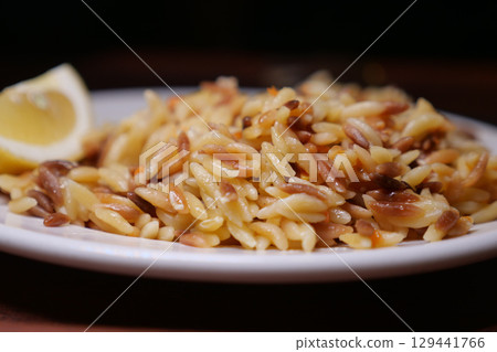 Delicious orzo pasta dish garnished with lemon 129441766
