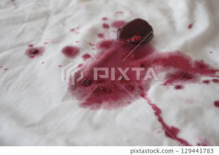red wine stains spread across a white piece of fabric 129441783